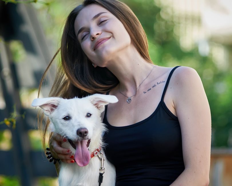 Mulher sorrindo abraçada ao seu cachorro feliz
